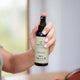 Hand holding a Sanctum product with a blurred background.