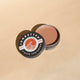 Sunbutter tinted sunscreen tin on a beige background