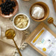 Assorted food items including dried fruits, yogurt, and a pack of supercharged food golden gut powder on a marble surface.