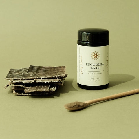 Eucumbia bark and a container of Eucommia bark powder on a green background.