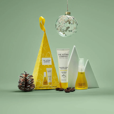 Cosmetic products and packaging from The Jojoba Company on a green background.