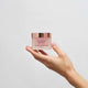 Hand holding a product from The Jojoba Company on a white background.