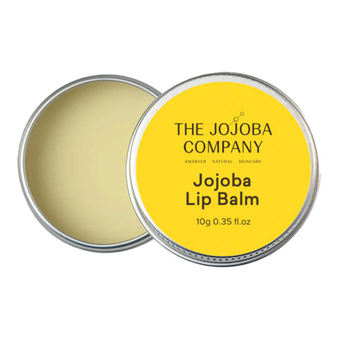 The Jojoba Company Jojoba Lip Balm 10g open silver tin showing pale balm, with the yellow lid leaning beside it on a plain white background