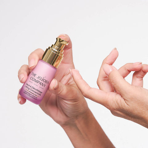Hand holding 30ml The Jojoba Company Neck & Décolletage Lifting Concentrate.