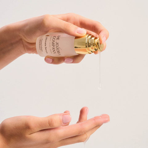 Hand holding a bottle of The Jojoba Company product with a clear background.