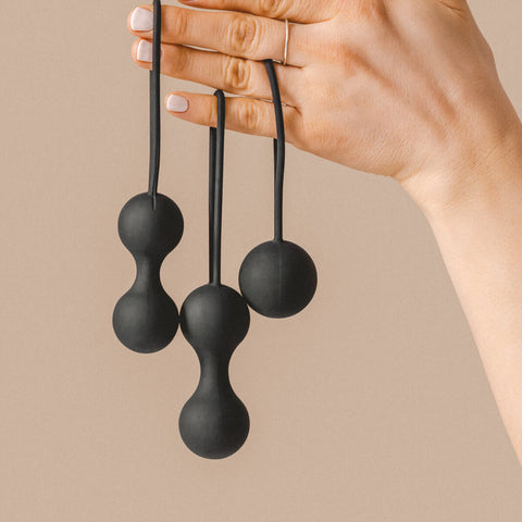 Hand holding The Natural Love Company Amyris, 3 black Kegal balls.