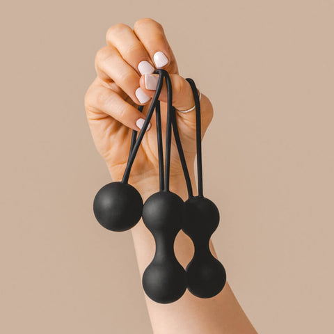 Hand holding The Natural Love Company Amyris, 3 black Kegal balls.