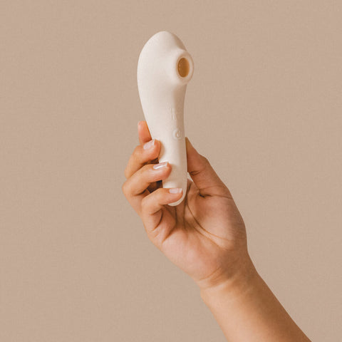 Hand holding The Natural Love Company Jasmine, a clitoral sucking vibrator.