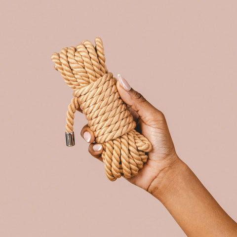 Hand holding The Natural Love Company Kanuka Bondage Rope, a versatile play rope 5 metres in length.