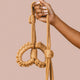 Hand holding The Natural Love Company Kanuka Handcuffs, soft handcuffs with control cord.