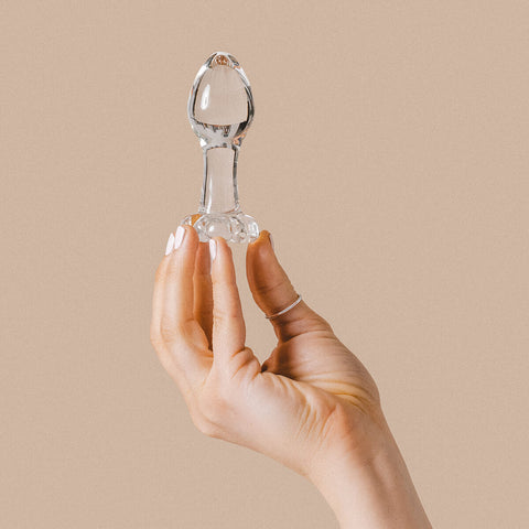 Hand holding The Natural Love Company Litsea, a classic tear drop shaped butt plug made of glass.