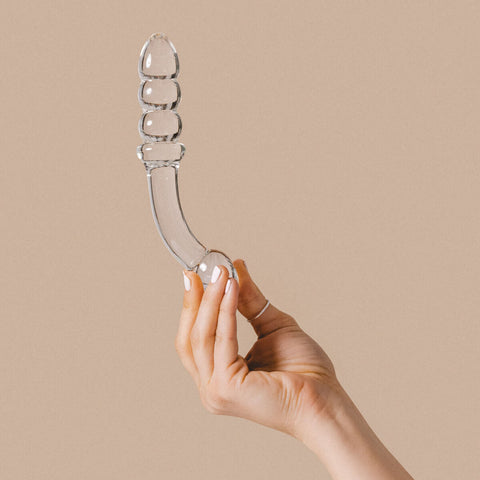 Hand holding The Natural Love Company Tansy G Curve, a 7 inch glass dildo.