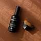 'Three Warriors face tan aqua mist bottle with a brush on a brown background.