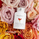 Unichi Rosa Prima Rosehip Extract 1500mg Complex 60 capsules lifestyle shot of the white bottle among pink, peach and yellow roses