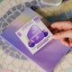 waterdrop Microdrink Boost Blackcurrant 12 servings lifestyle shot of a hand holding the purple box over a colourful tiled surface