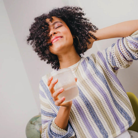 Woman wearing a striped sweater holding a glass of water indoors.