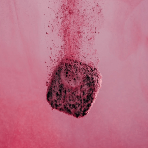 waterdrop Microdrink Taster Pack lifestyle shot of a dark berry cube dropping into pink water with fizzing bubbles, styled lifestyle photo