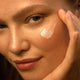 Close-up of a person applying Skin Food cream to their face.