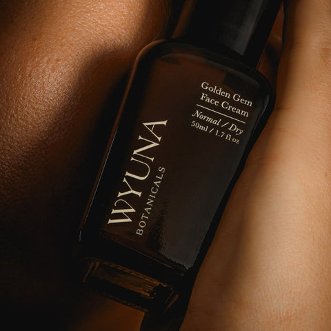 Wyuna Botanicals Golden Gem Face Cream 50ml lifestyle close up of the dark bottle against bare skin, styled lifestyle photo, single image