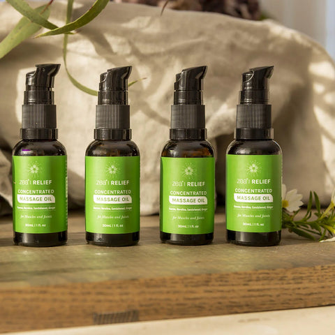 Zea Relief Kunzea Concentrated Massage Oil 30ml lifestyle shot of four dark bottles with green labels in a row on wood, styled lifestyle photo